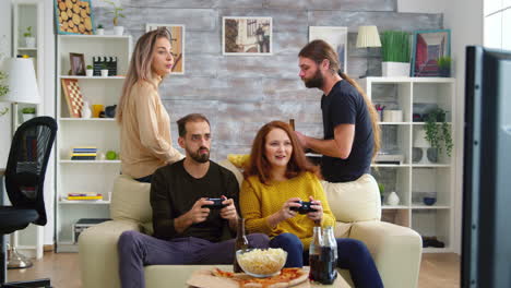 novia de pelo rojo tratando de golpear a su amigo mientras juega videojuegos