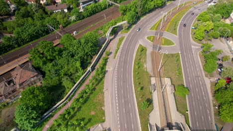 Aerial-tilt-up-shot-of-highway,-rails-and-cityscape-of-Gdansk-in-background-during-sunny-day,Poland---Establishing-shot