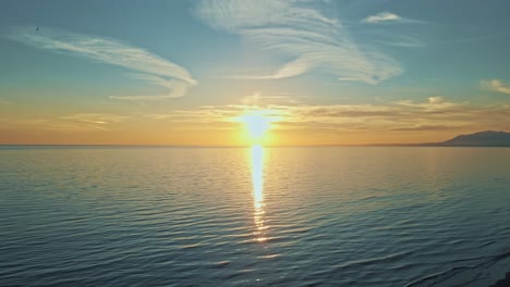 Drone-slowly-going-lower-at-the-beach,-with-people-passing-by