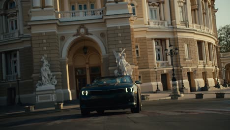 a beautiful dark gray cabriolet makes a turn in front of a building with amazing renaissance architecture