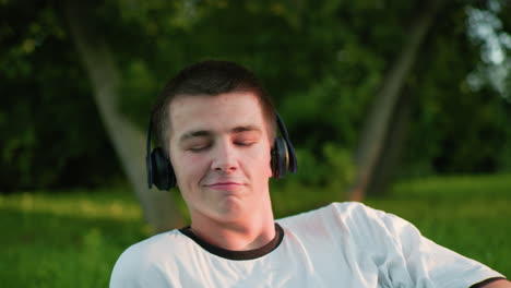 artista de música con auriculares asintiendo con la cabeza disfrutando de la música con una sonrisa sutil y mirando hacia arriba pensativo, rodeado de vegetación y árboles