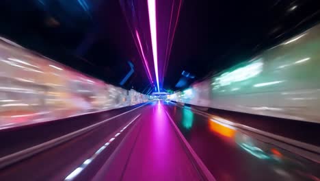 el coche avanza a través de túneles brillantemente iluminados, mostrando el vibrante horizonte de hong kong por la noche. las luces de colores crean una atmósfera enérgica