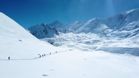 Tiro-De-Drone-De-Tierra-Nevada-En-Manang-Nepal-Donde-La-Gente-Camina-En-Un-Largo-Sendero-Alrededor-De-La-Montaña-Nevada