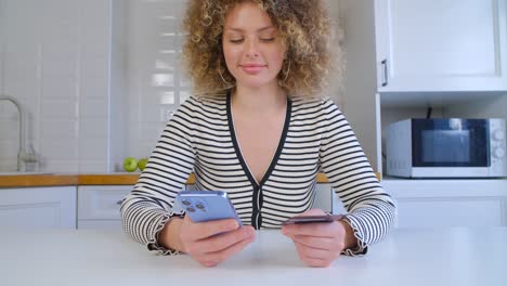 compras en línea con tarjeta de crédito. mujer joven comprando en la tienda web aplicación con teléfono inteligente moderno. hermosa mujer blanca con cabello rizado haciendo transferencia de dinero con nuevo teléfono móvil