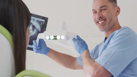 un dentista caucásico sonriente preparando a una paciente femenina en una clínica dental moderna
