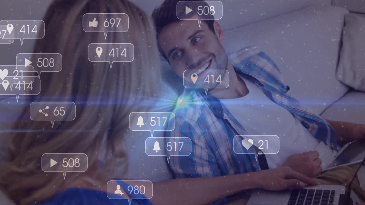animación de iconos de redes sociales con números sobre una pareja caucásica usando una computadora portátil.
