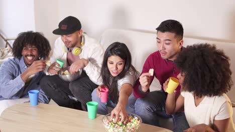 diverse group of friends enjoying a movie night at home with popcorn and drinks