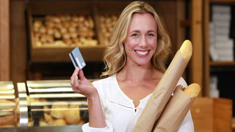 Smiling-blonde-with-paper-bags-showing-credit-card