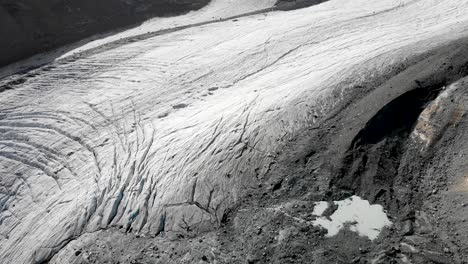 aerial flyover over the allalin glacier near saas-fee in valais, switzerland with a pan up view from the crevasses and ice up to the rimpfischhorn and strahlhorn on a sunny day in the swiss alps