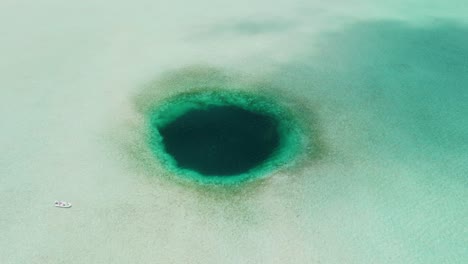 high aerial view of bahamas blue hole with fishing boat approaching