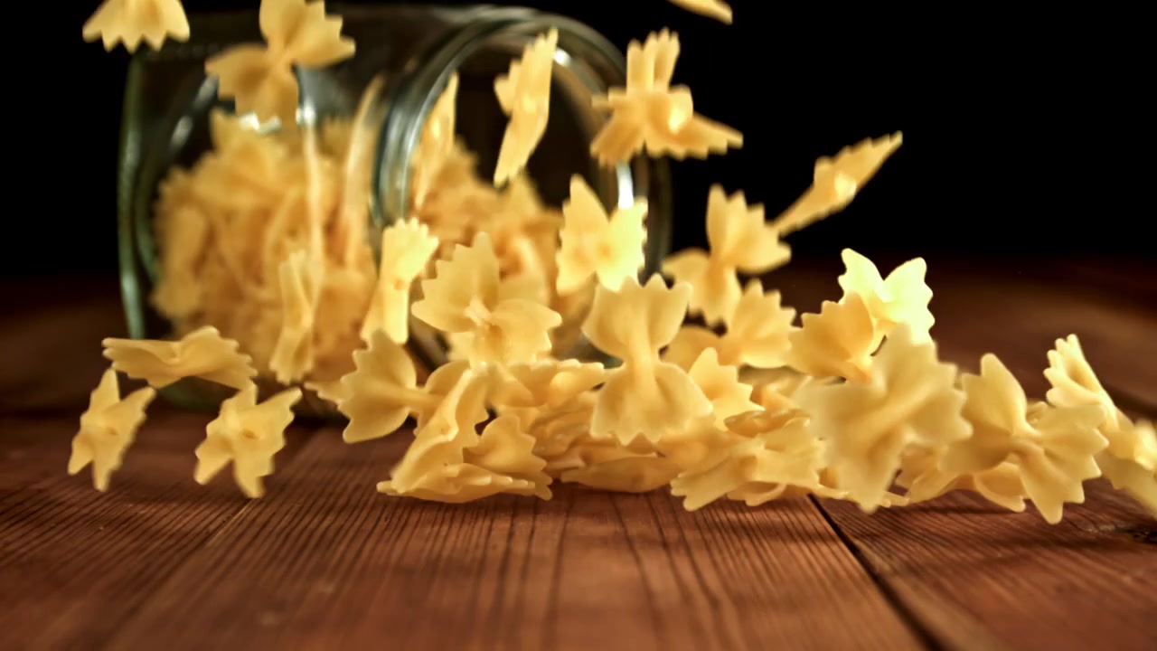 Pasta farfalle che cade al rallentatore su un tavolo di legno