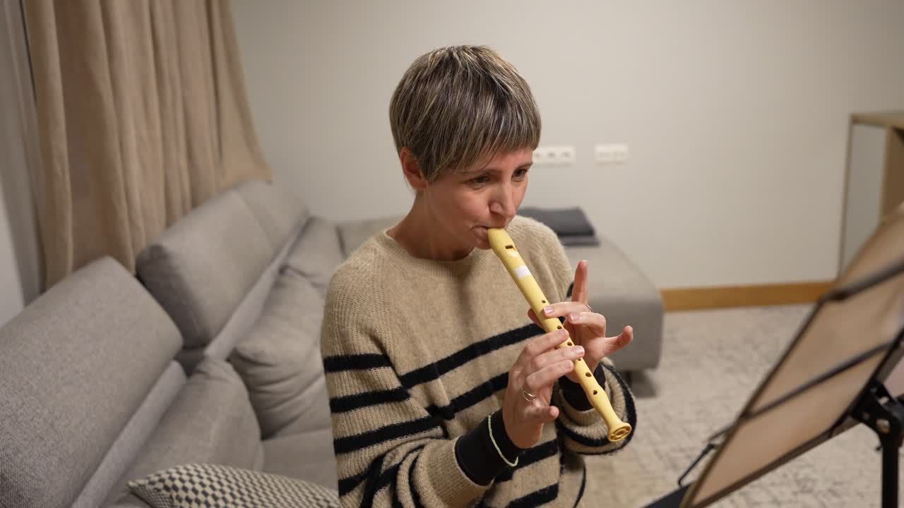 Donna che suona il flauto dolce e legge uno spartito musicale a casa