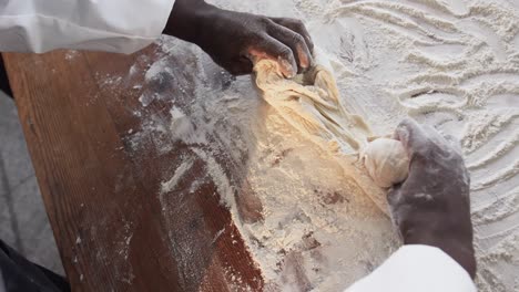 panadero afroamericano que trabaja en la cocina de la panadería, amasando la masa en el mostrador en cámara lenta