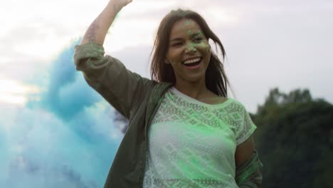 Multiracial-woman-dancing-with-coloured-smoke-bombs-at-Holi-Festival.