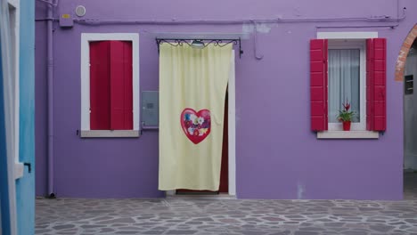 vibrant purple house with red shutters and heart curtain