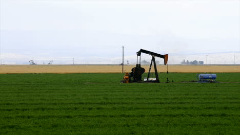 Lapso-De-Tiempo-De-Un-Pozo-De-Petróleo-Bombeando-En-Medio-De-Un-Campo-De-Cultivo