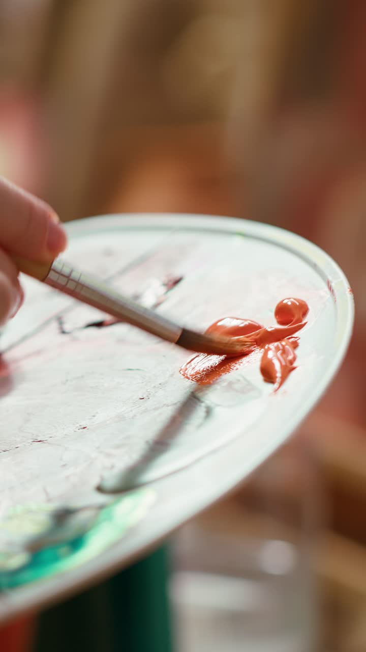 Close-up of Hand Mixing Orange Paint on an Artist's Palette