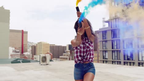 mujer joven de moda en el techo urbano usando granadas de humo