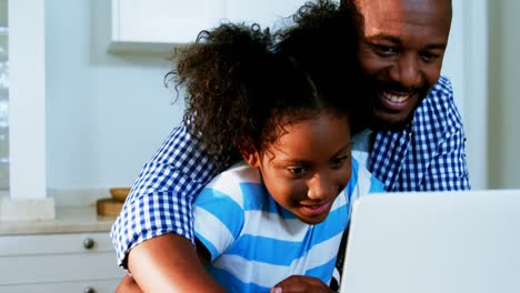 Father-and-daughter-using-laptop-in-kitchen