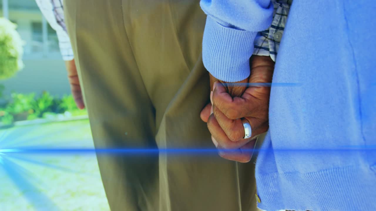 Animation of light moving over midsection of senior couple walking holding hands