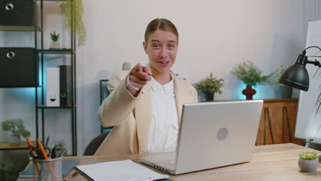 mujer de negocios trabajando en una computadora portátil de oficina apuntando a la cámara buscando una expresión feliz, haciendo una elección