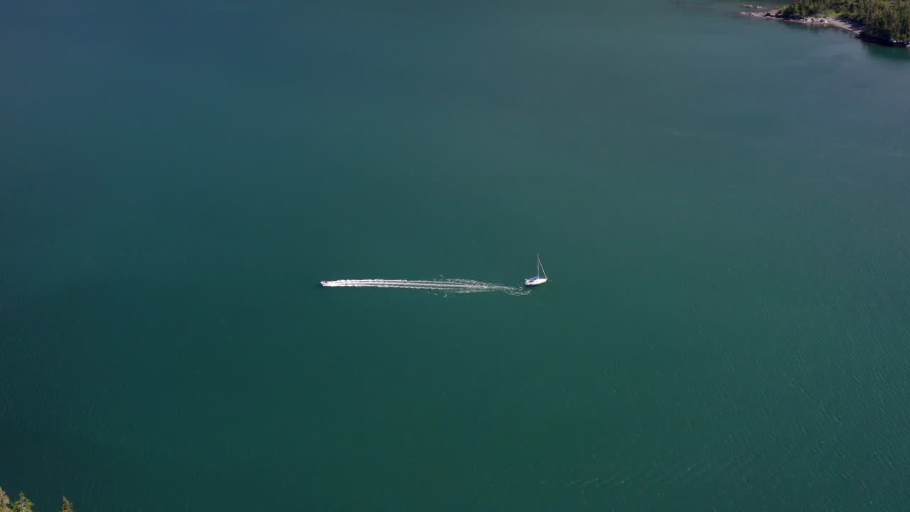 Inflatable Motor Boat Leaving Yacht Floating On Calm Waters In Alaska. - aerial static