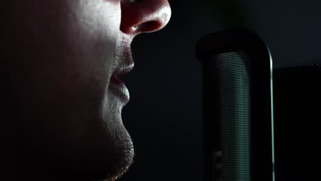 man talking into a microphone front of computer, streamer speaking into mic, dark room - static shot