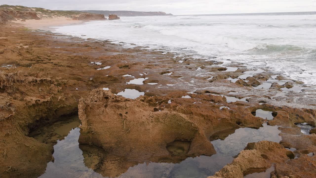 las olas del océano golpean las piscinas de roca en una playa