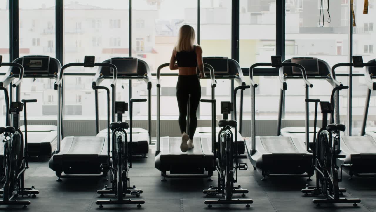 женщина занимается на беговой дорожке в тренажерном зале