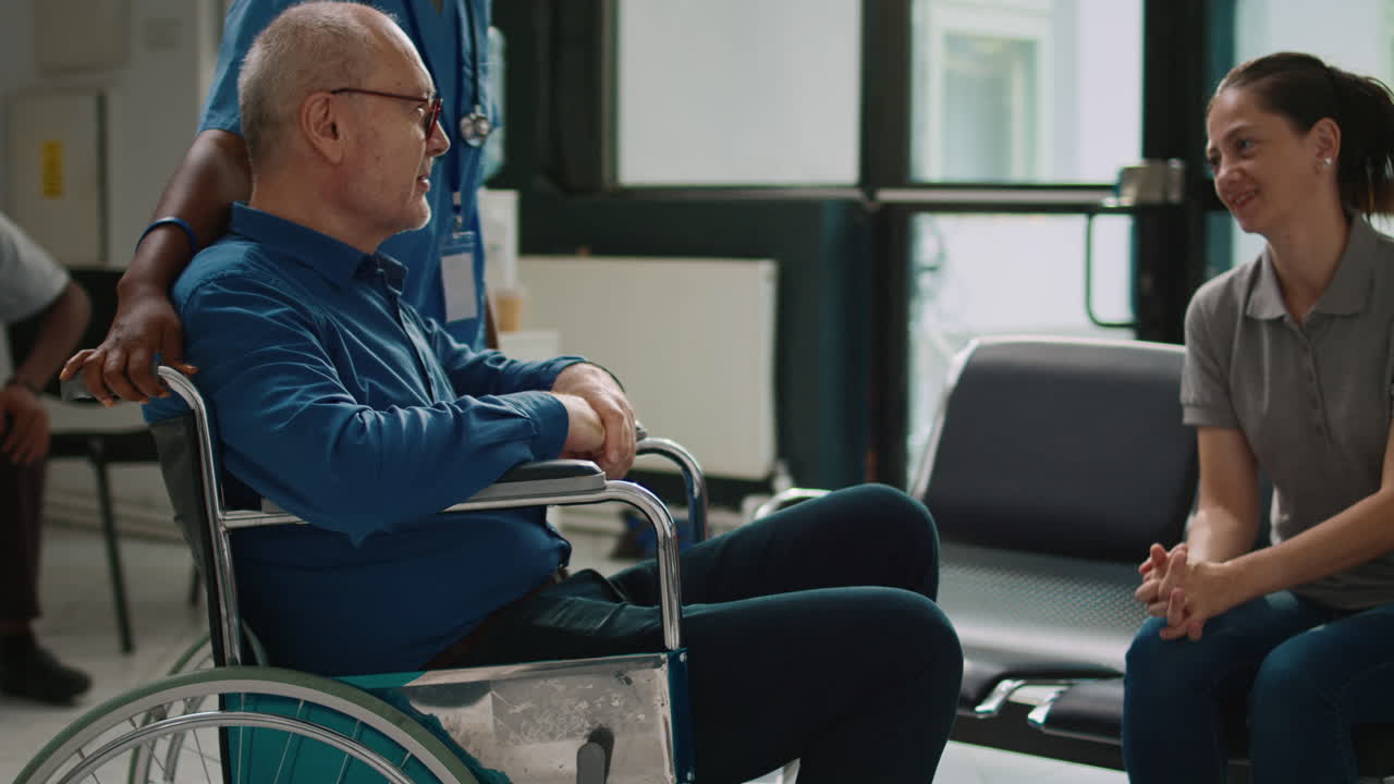 Nurse helping man in wheelchair to meet with family in clinic lobby