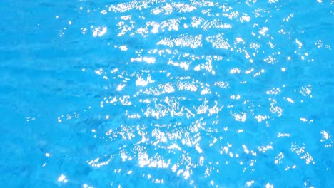 water ripples and sun highlight in swimming pool background