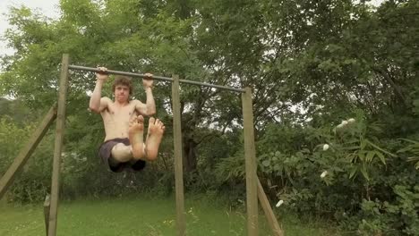 Athletic young man does L-Sit pullups on outdoor home gym