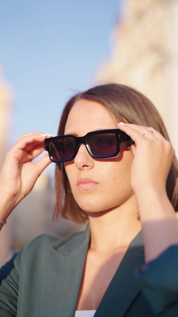 Verticaal - Kaukasische vrouw zet in fel daglicht een zonnebril op, Praag