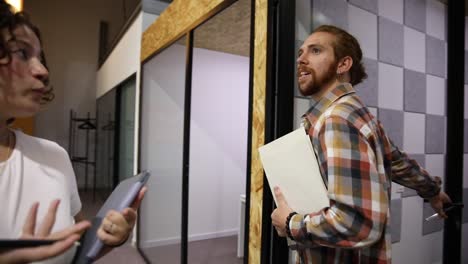 young coworkers walking in office and discussing project