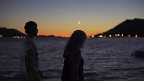 two adults peacefully walking by the seaside in an island at dusk in croatia. selective focus