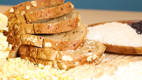 a variety of grains and sliced bread are artfully arranged on a wooden surface under bright lighting, showcasing texture and color
