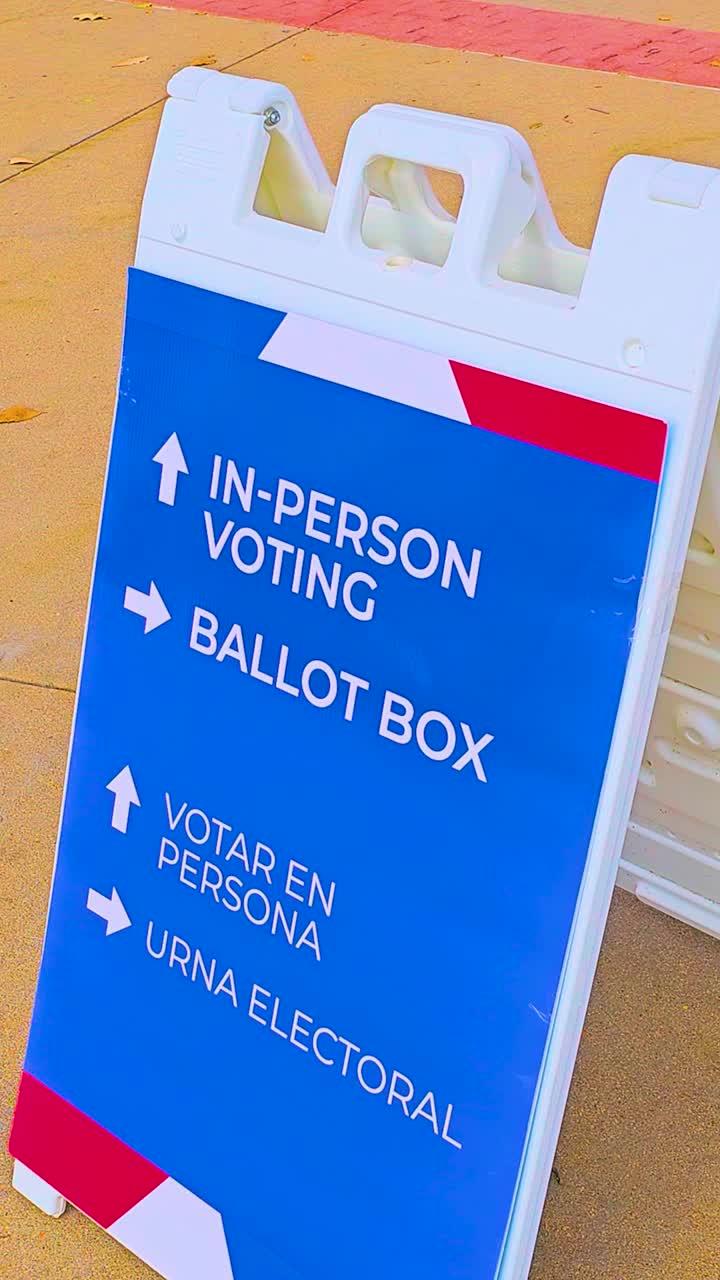 Vertical ballot box sign with large arrows directs citizens to the polling place, with Spanish text Votar en Persona and Urna Electoral emphasizing civic duty, democracy, accessibility, participation