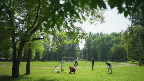 한 가족이 잔디에서 야외에서 즐거운 하루를 보내고 있는데, 한 소년은 골포스트 근처에 신발를 고, 다른 소년들은 축구를 하고 운동을 하고 있다.