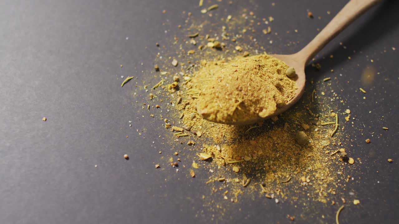 Video of spoon with tumeric seasoning lying on grey surface