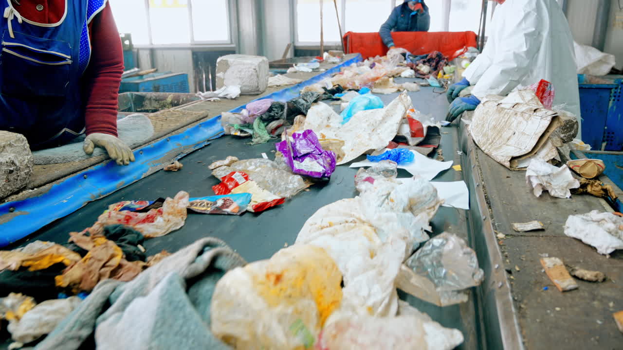 Workers in special wear sorting garbage on a conveyor belt at waste sorting plant