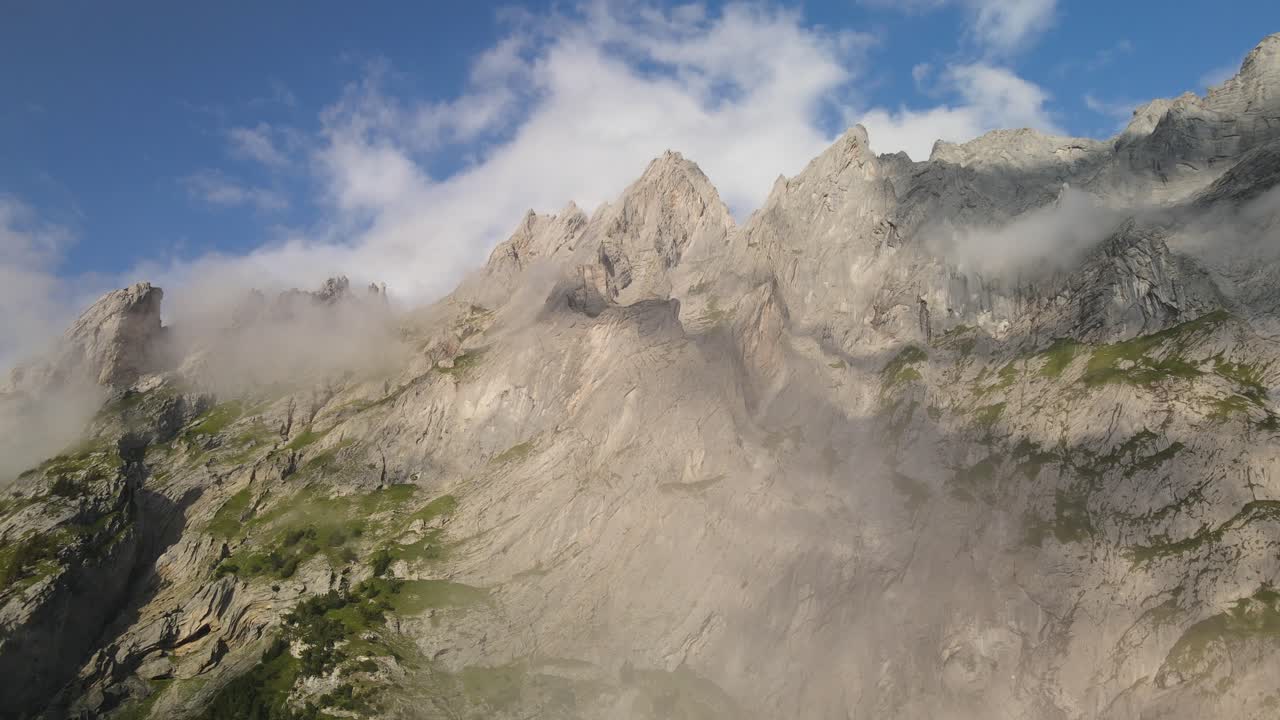 Luftfoto af Wendenstöcke-bjerget taget med drone, der viser kalkstentoppe langs Via Alpina i Schweiz med stejle alpine klipper, erosionsmønstre og dramatiske bevægelser af skyerne i de centrale schweiziske alper