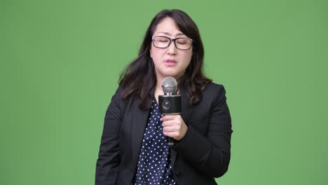 mature sad asian businesswoman as newscaster using microphone