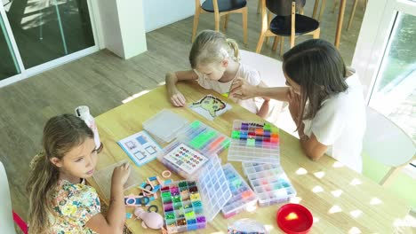 mother and daughters beading together