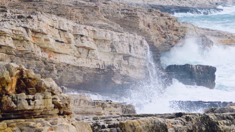 Big-waves-breaking-on-rocky-shore-creating-mist-and-foam