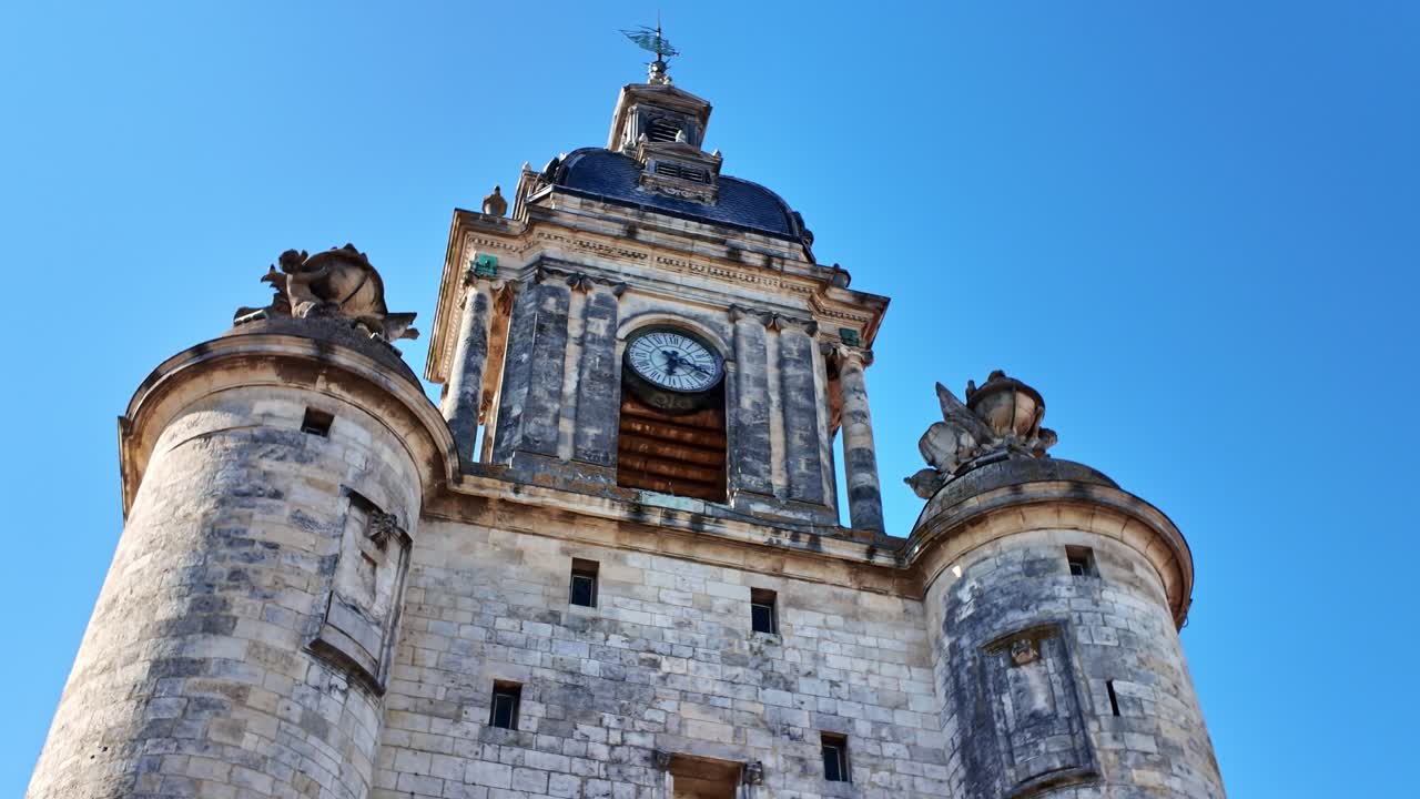Nærbillede fra lav vinkel på jordniveau af klokketårnet Grosse Horloge i La Rochelle mod en klar blå himmel - Frankrig.