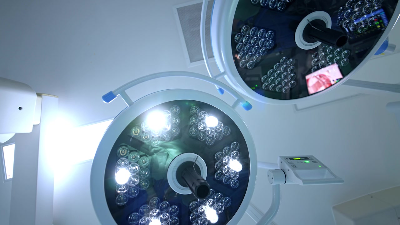 Dos lámparas redondas en el techo de la sala de cirugía. Una de las lámparas está encendida. Vista de ángulo bajo del equipo de iluminación en el hospital