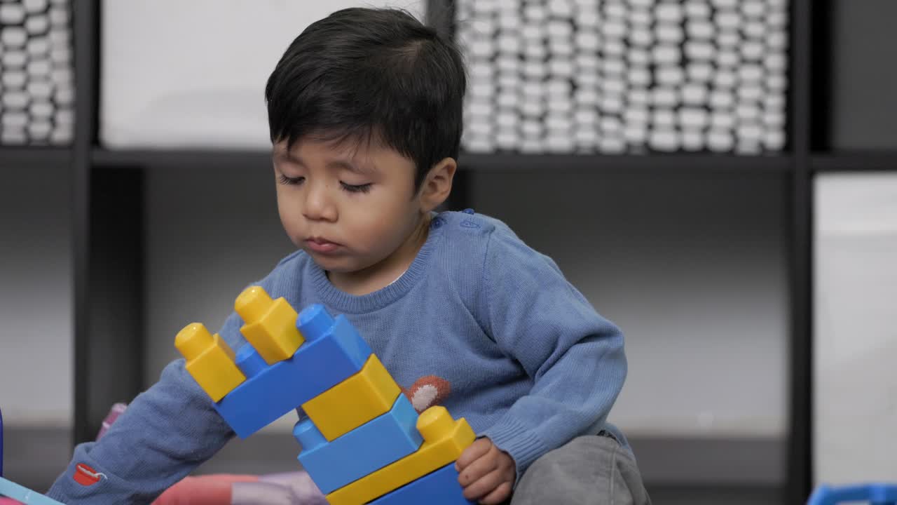 niño mexicano de dos años jugando con juguetes didácticos en casa