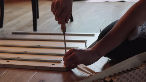 close up of teenage boy assembling a flat pack shelf on the floor