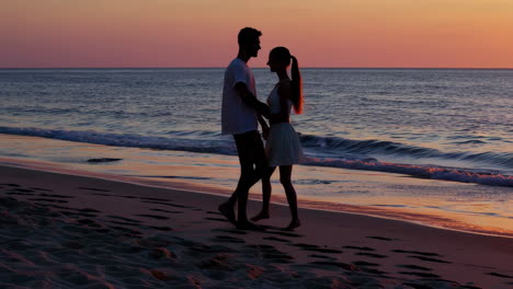 couple walking on beach at sunset