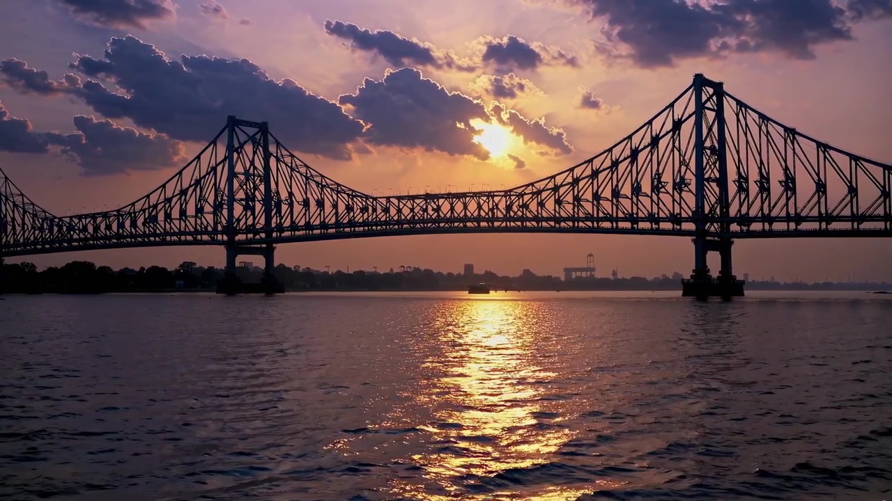 Silhouette di un grande ponte a traliccio sull'acqua al tramonto